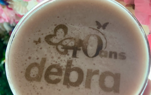 Latte art with "40 ans DEBRA" logo at DEBRA France’s 40th anniversary event, celebrating decades of support for the EB community.