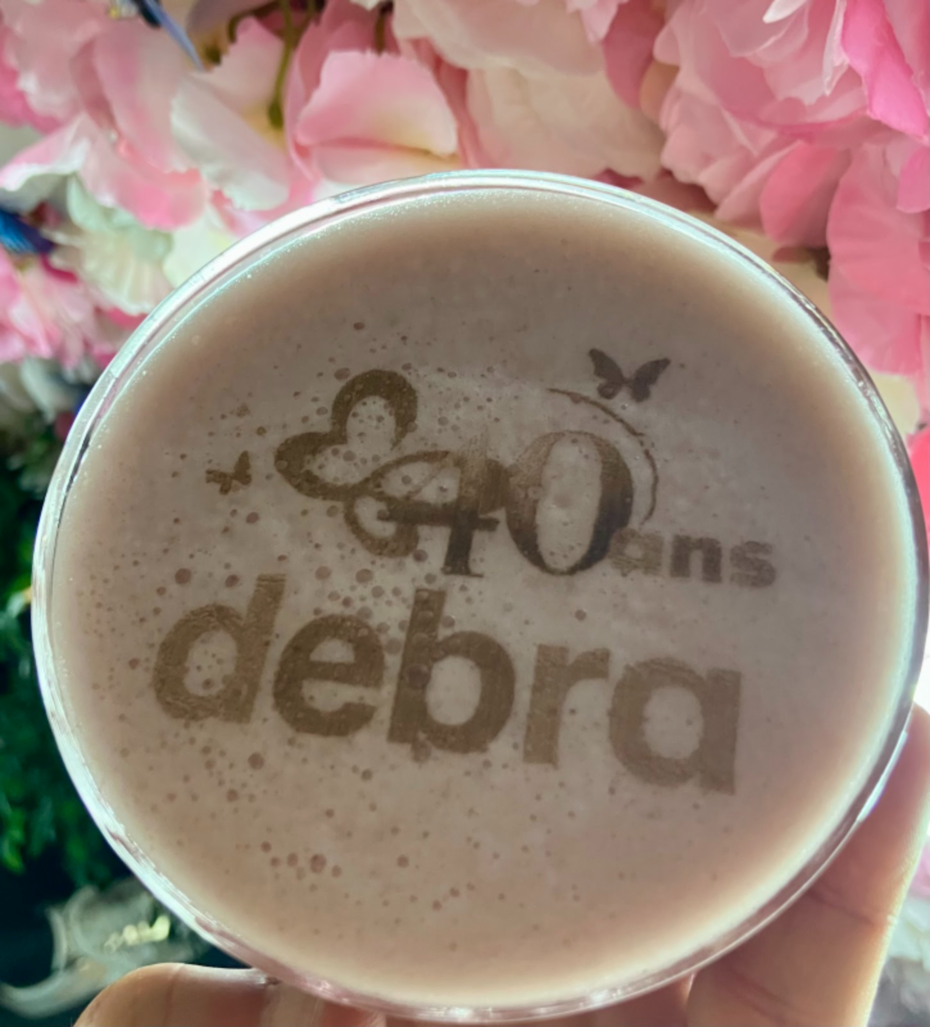 Latte art with "40 ans DEBRA" logo at DEBRA France’s 40th anniversary event, celebrating decades of support for the EB community.